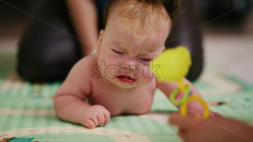 A small baby lying on their tummy and back on a padded surface