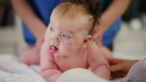 Baby lying on their tummy while an adult massages them and performs mobility exercises