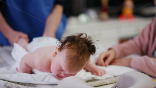 Baby lying on their tummy while an adult massages them and performs mobility exercises