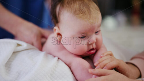 Baby lying on their tummy while an adult massages them and performs mobility exercises