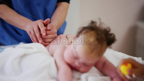 Baby lying on their tummy while an adult massages them and performs mobility exercises