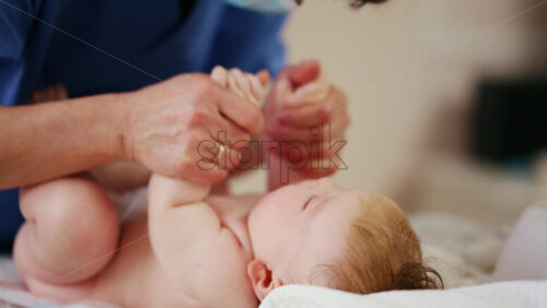 Baby lying on their back while an adult massages them and performs mobility exercises