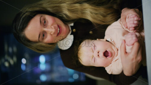 A warm moment of a woman holding her baby in a restaurant. Vertical