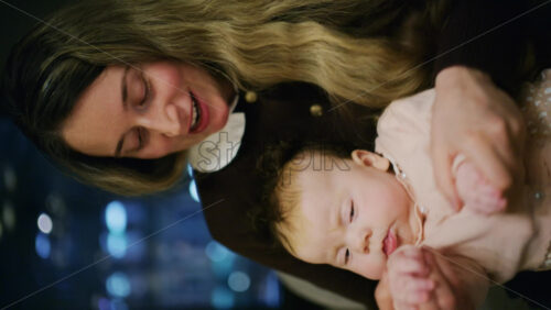A warm moment of a woman holding her baby in a restaurant. Vertical