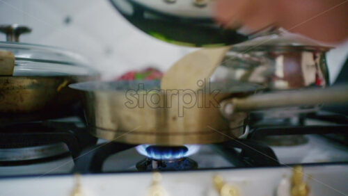 Close up of a pot on a gas stove with a visible blue flame heating from below