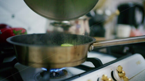Close up of a pot on a gas stove with a visible blue flame heating from below