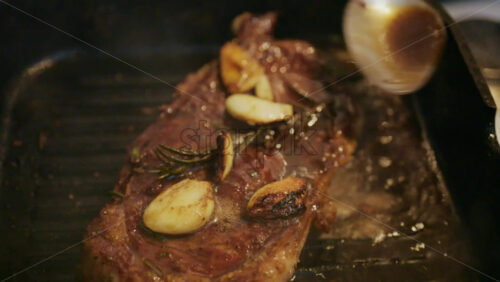 Close up of a juicy steak sizzling in a grill pan while being pressed with a spatula
