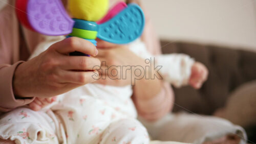 Baby holding a bright, colorful toy while sitting on a parent's lap