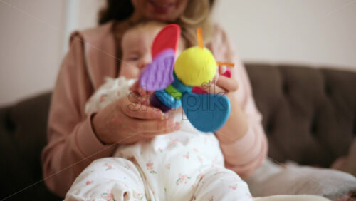 Baby holding a bright, colorful toy while sitting on a parent's lap