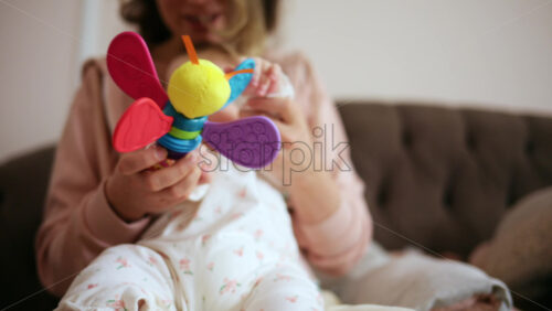Baby holding a bright, colorful toy while sitting on a parent's lap