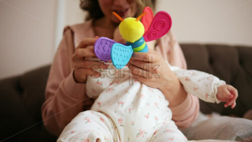 Baby holding a bright, colorful toy while sitting on a parent's lap