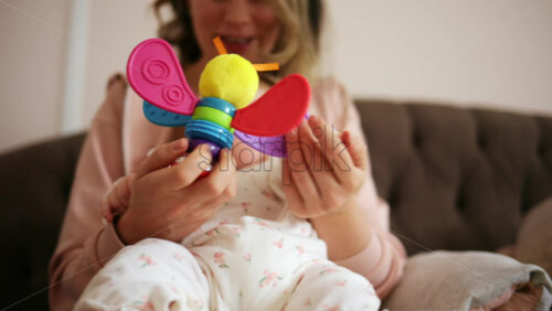 Baby holding a bright, colorful toy while sitting on a parent's lap