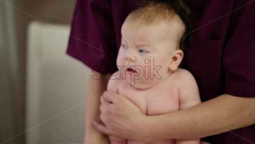 Baby sitting upright while being supported by an adult, showing effort and focus