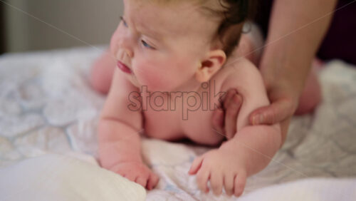 Baby lying on their tummy while an adult massages them and performs mobility exercises