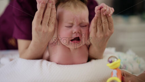 Baby lying on their tummy while an adult massages them and performs mobility exercises