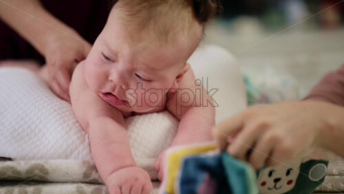 Baby lying on their tummy while an adult massages them and performs mobility exercises