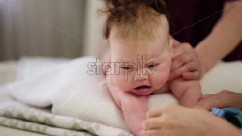 Baby lying on their tummy while an adult massages them and performs mobility exercises