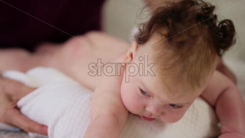 Baby lying on their tummy while an adult massages them and performs mobility exercises