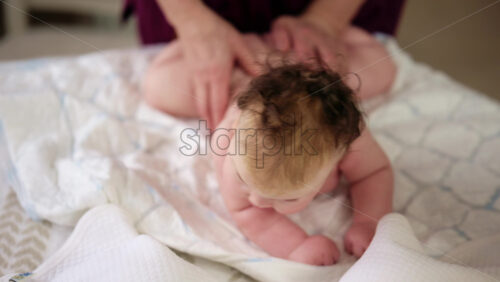 Baby lying on their tummy while an adult massages them and performs mobility exercises