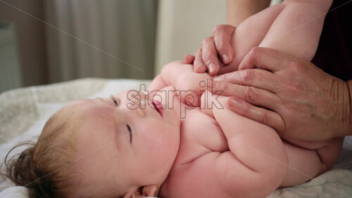 Baby lying on their back while an adult massages them and performs mobility exercises