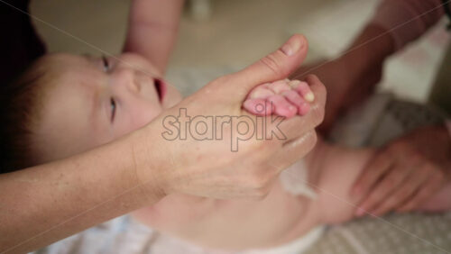 Baby lying on their back while an adult massages them and performs mobility exercises