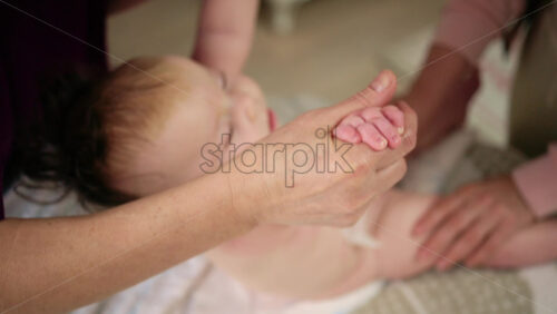 Baby lying on their back while an adult massages them and performs mobility exercises