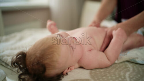 Baby lying on their back while an adult massages them and performs mobility exercises
