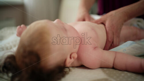 Baby lying on their back while an adult massages them and performs mobility exercises