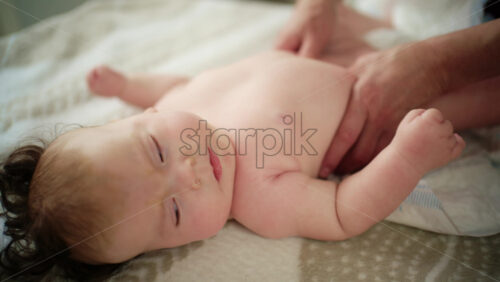 Baby lying on their back while an adult massages them and performs mobility exercises