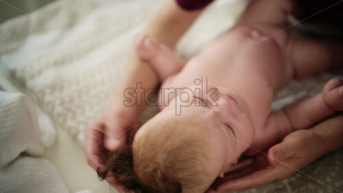 Baby lying on their back while an adult massages them and performs mobility exercises