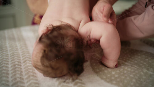 Baby lying on their tummy while an adult massages them and performs mobility exercises