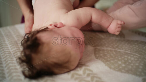 Baby lying on their tummy while an adult massages them and performs mobility exercises