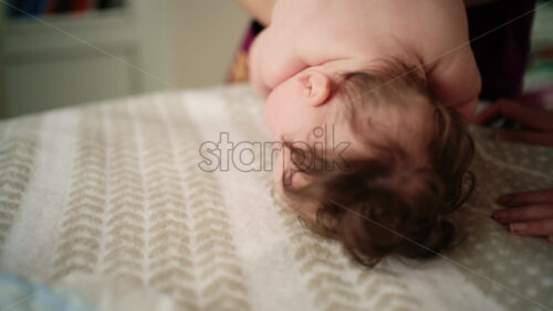 Baby lying on their tummy while an adult massages them and performs mobility exercises