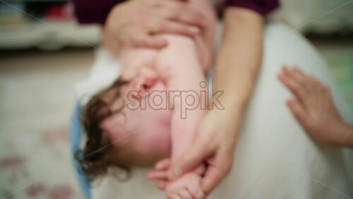 Baby placed on tummy on a stability ball while adults support the infant's torso and shoulders