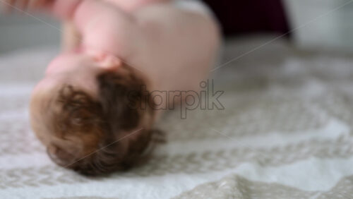 Baby lying on their back while an adult massages them and performs mobility exercises