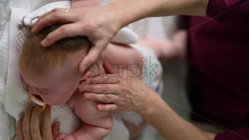 Baby lying on their tummy while an adult massages them and performs mobility exercises