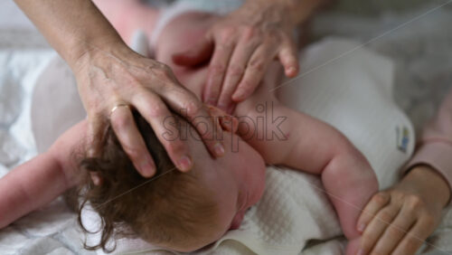 Baby lying on their tummy while an adult massages them and performs mobility exercises