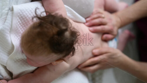 Baby lying on their tummy while an adult massages them and performs mobility exercises