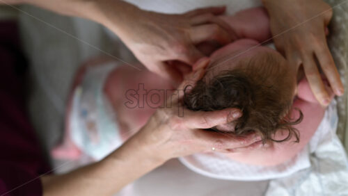 Baby lying on their back while an adult massages them and performs mobility exercises