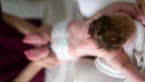 Baby lying on their tummy while an adult massages them and performs mobility exercises