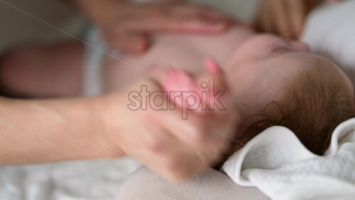 Close up of adult hands gently massaging a baby's arm and palm