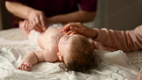 Baby lying on their back while an adult massages them and the mother holds the pacifier in the baby's mouth