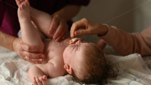 Baby lying on their back while an adult massages them and the mother gently holds the baby's hand