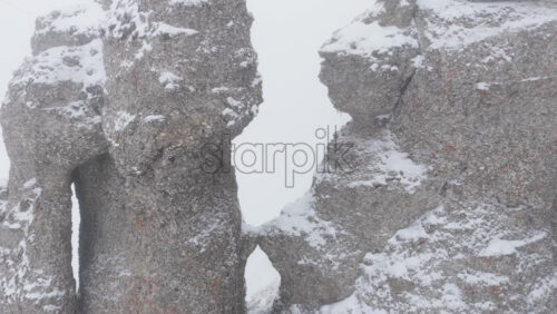 Aerial drone view of Babele la Sfat (Old Ladies's Council) rock formation covered in snow in winter season. Romania, Carpathian Mountains