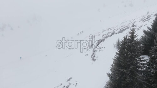 Aerial drone view of people hiking on Ciucas peak covered in snow in winter season. Romania, Carpathian Mountains