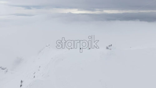 Aerial drone view of people hiking on Ciucas peak covered in snow in winter season. Romania, Carpathian Mountains