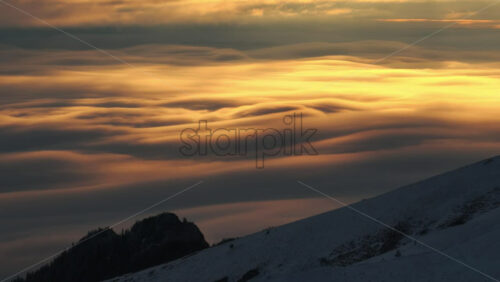 Panoramic aerial drone view of golden sunrise above clouds, winter landscape in the mountains. Transylvania, Mount Ciucas in Romania