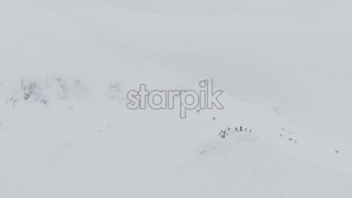 Aerial drone view of people hiking on Ciucas peak covered in snow in winter season. Romania, Carpathian Mountains