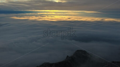 Panoramic aerial drone view of golden sunrise above clouds, winter landscape in the mountains. Transylvania, Mount Ciucas in Romania
