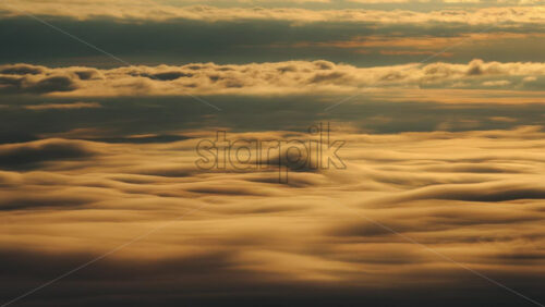 Panoramic aerial drone view of golden sunrise above clouds, winter landscape in the mountains. Transylvania, Mount Ciucas in Romania